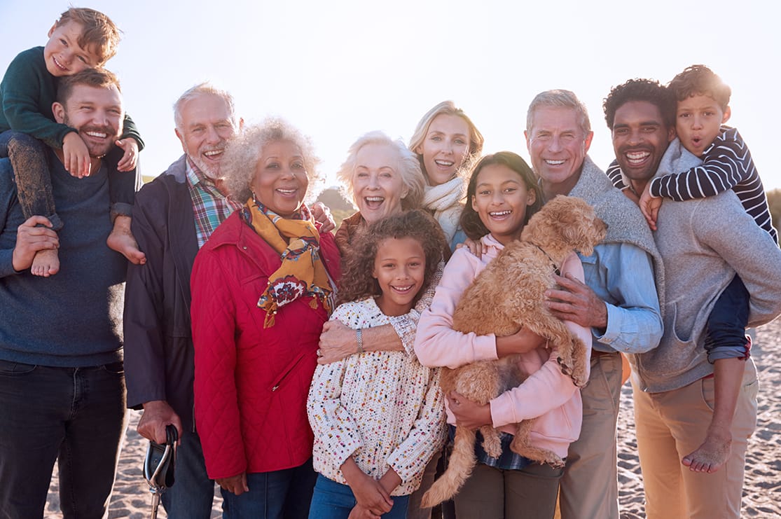 Portrait Of Multi-ethnic, Multi-Generation Family Group With Dog On beach in winter